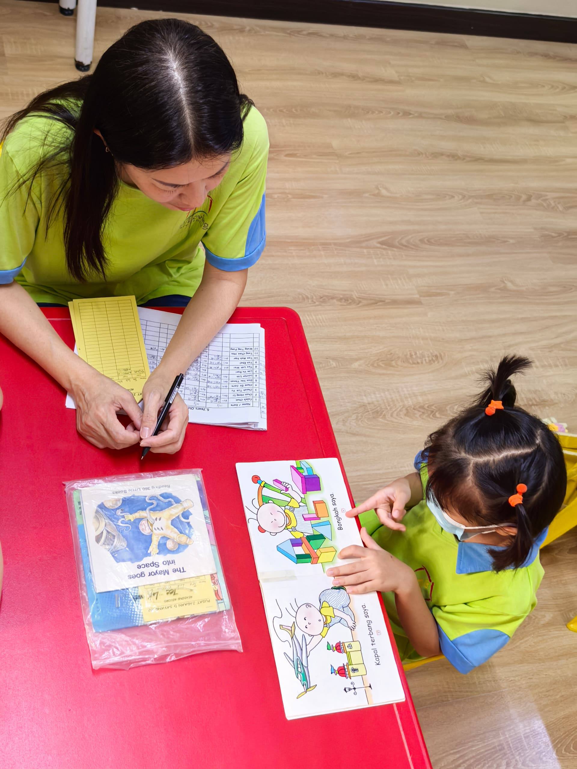 A Dloving Care and Learning Team member guiding a child during one-to-one reading
