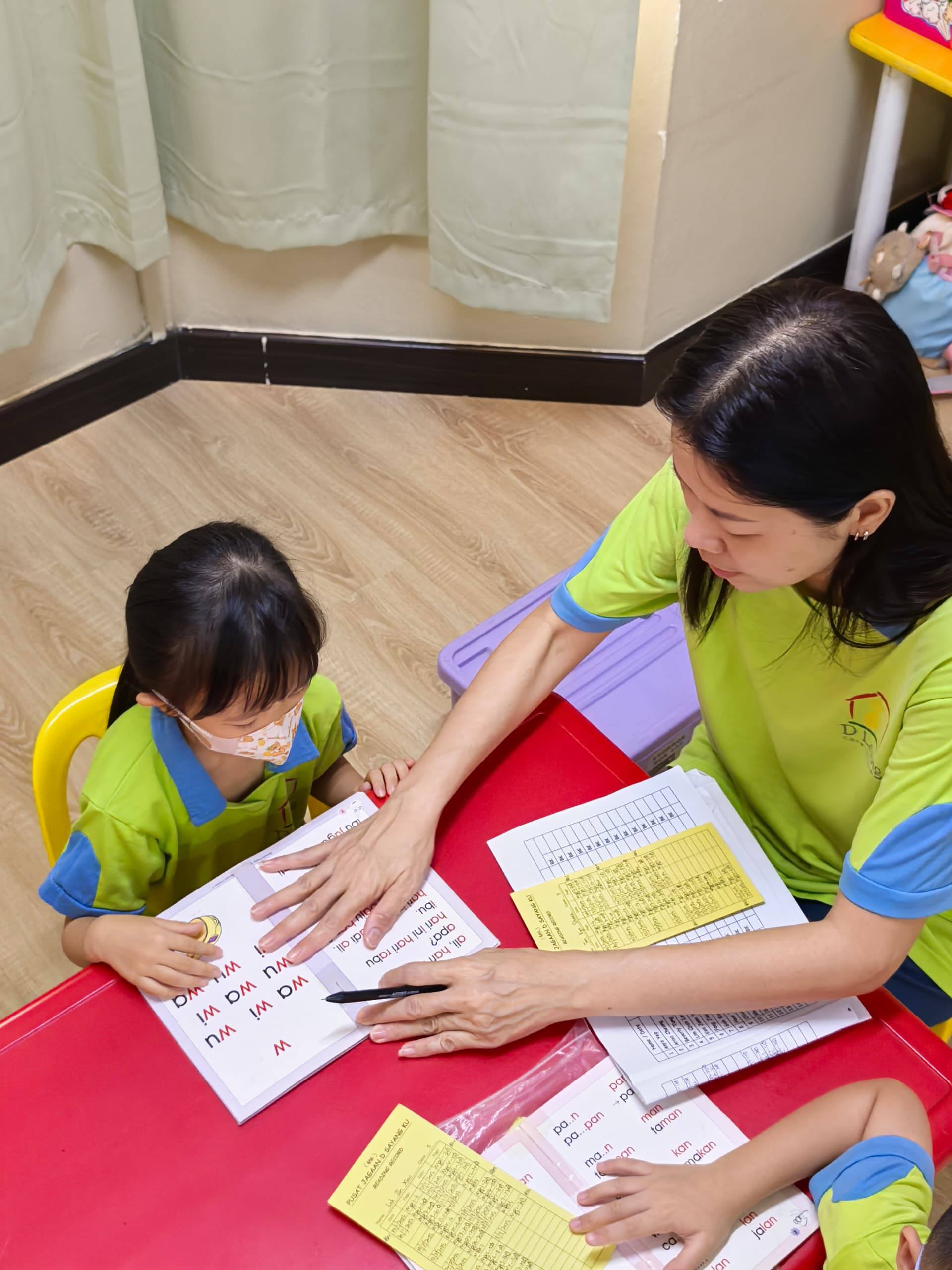 A Dloving Care and Learning Team member reading one-to-one with a child