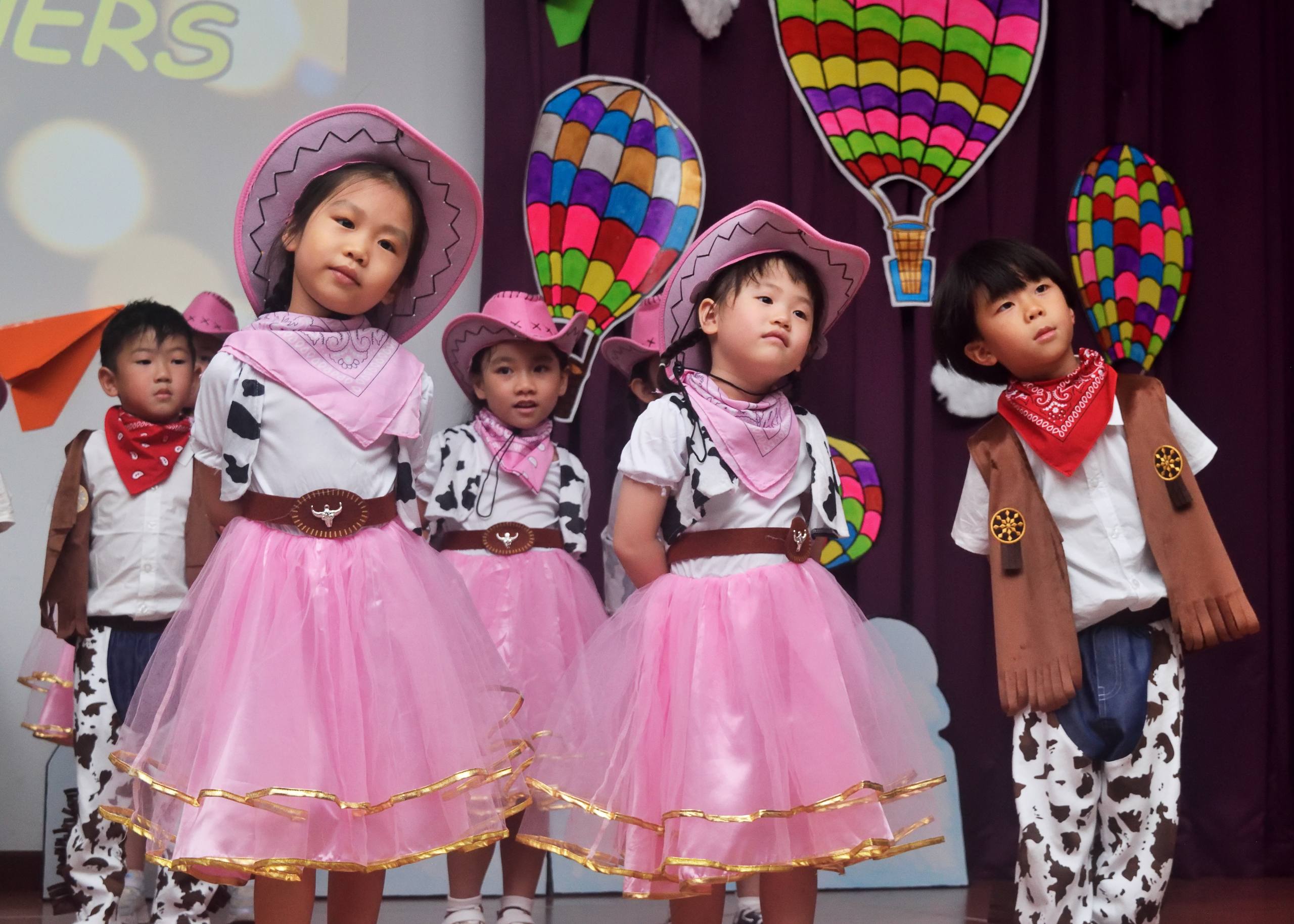 Children in colourful cowboy costumes performing at a Dloving yearly concert