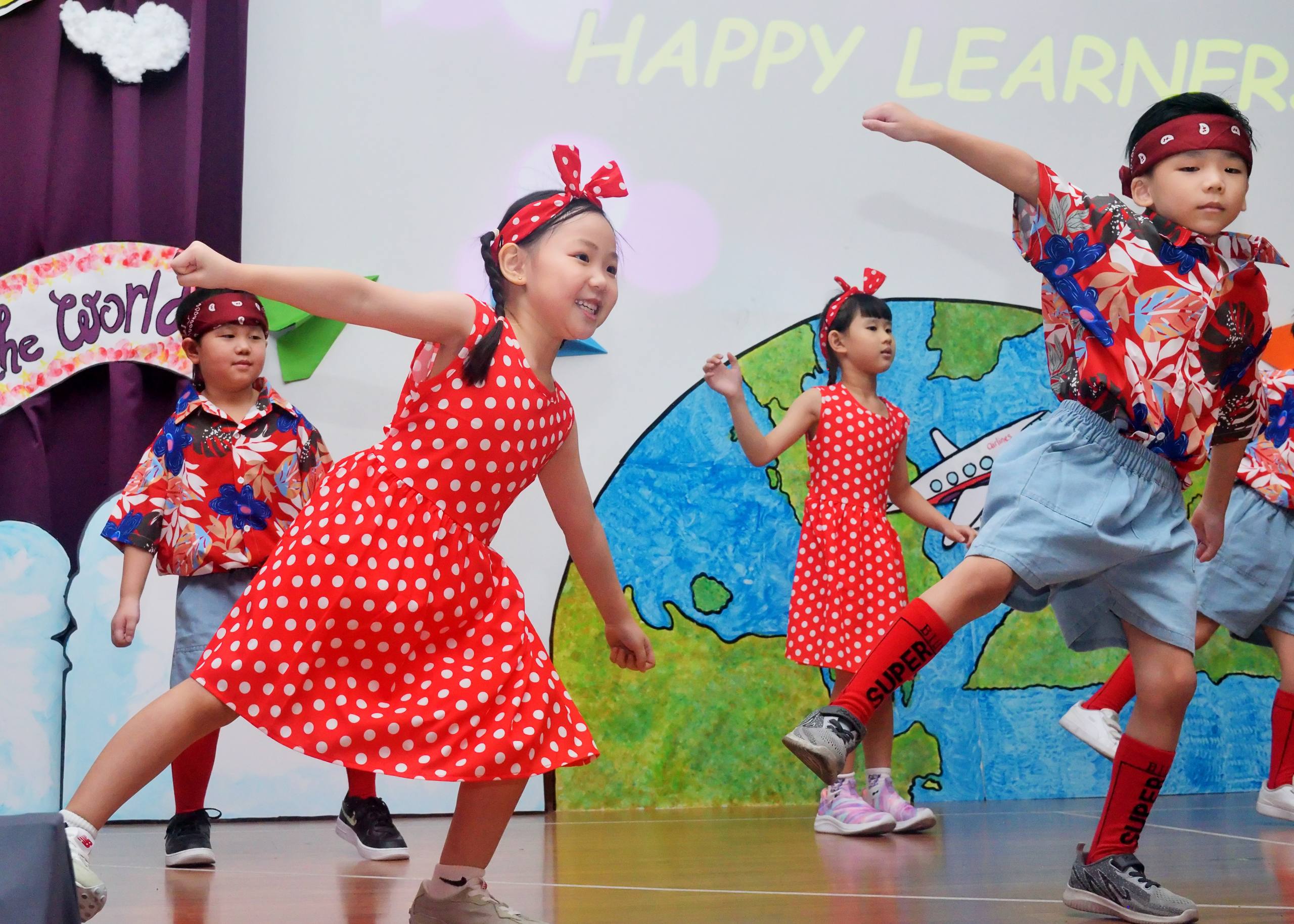 Children dancing in red costumes during a Dloving yearly concert